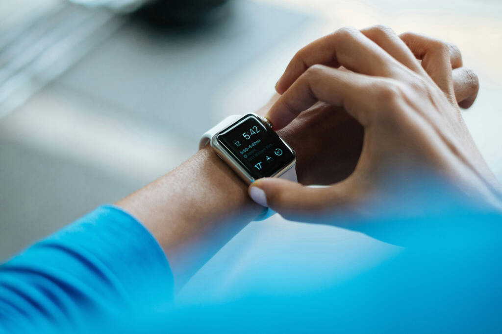 Person looking at their fitness statistics on their watch wearing a blue shirt.